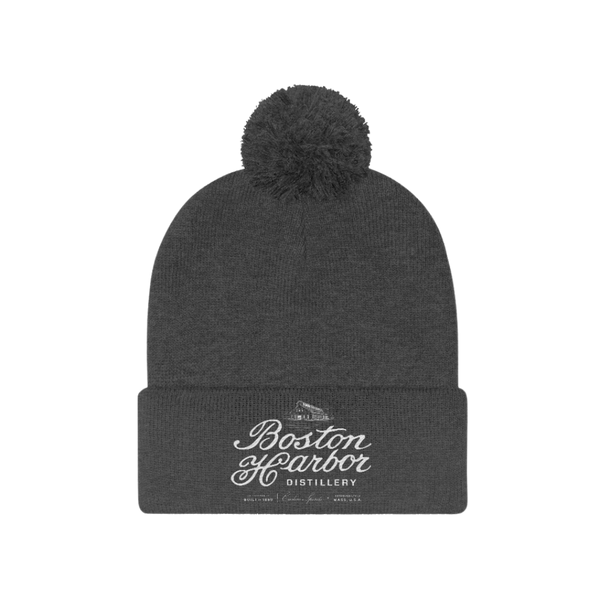 An image of a Boston Harbor Distillery pom pom beanie in Graphite Heather
