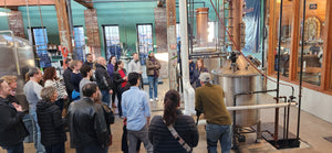 An Image of a group of people standing around copper top stills at Boston Harbor Distillery