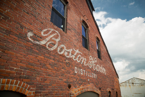 Wider shot of our front facade brick building with white painted Boston Harbor Distillery logo