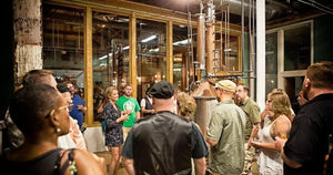 Image is of a group of people on a tour in Boston Harbor Distillery's production room surrounding our copper top still.