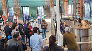 An Image of a group of people standing around copper top stills at Boston Harbor Distillery